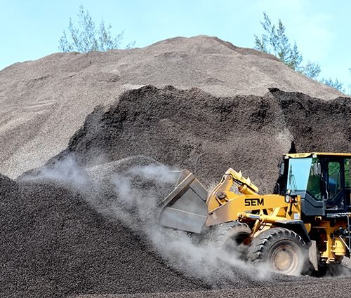 Bengkulu, Indonesia, January 18, 2023: Workers are collecting palm kernel shells using equipment and bulldozer vehicles that will be prepared for export as bio-energy feedstock